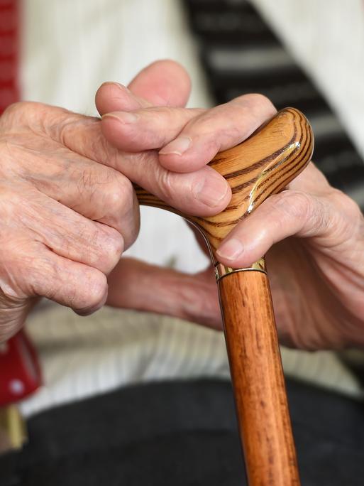 Ein älterer Parkinson-Patient, der einen Gehstock hält.