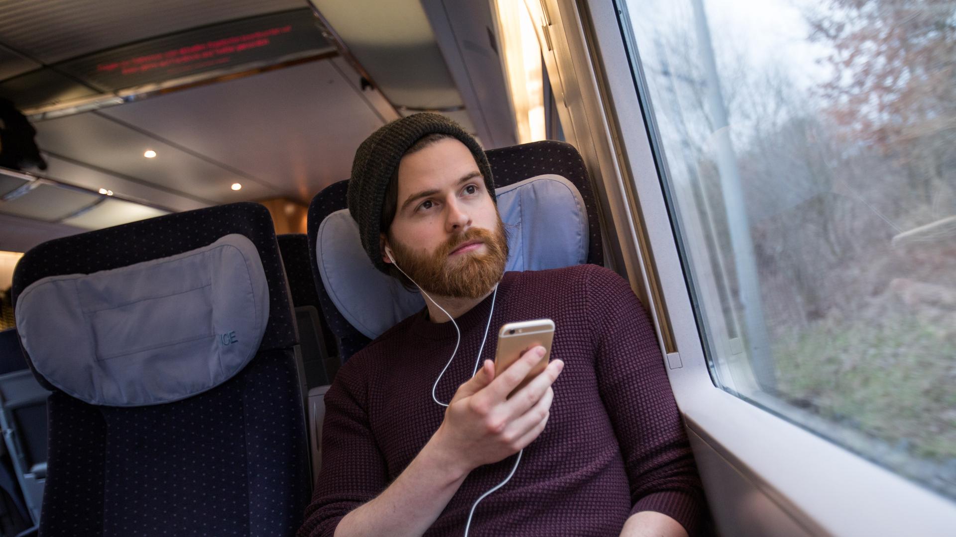 ILLUSTRATION - Ein Mann sitzt am 28.03.2018 in einem ICE von Luebeck nach Hamburg und benutzt sein Smartphone.