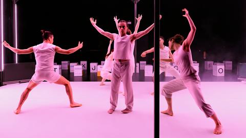 Auf einer pink beleuchteten Bühnen tanzen Personen in weißer Kleidung