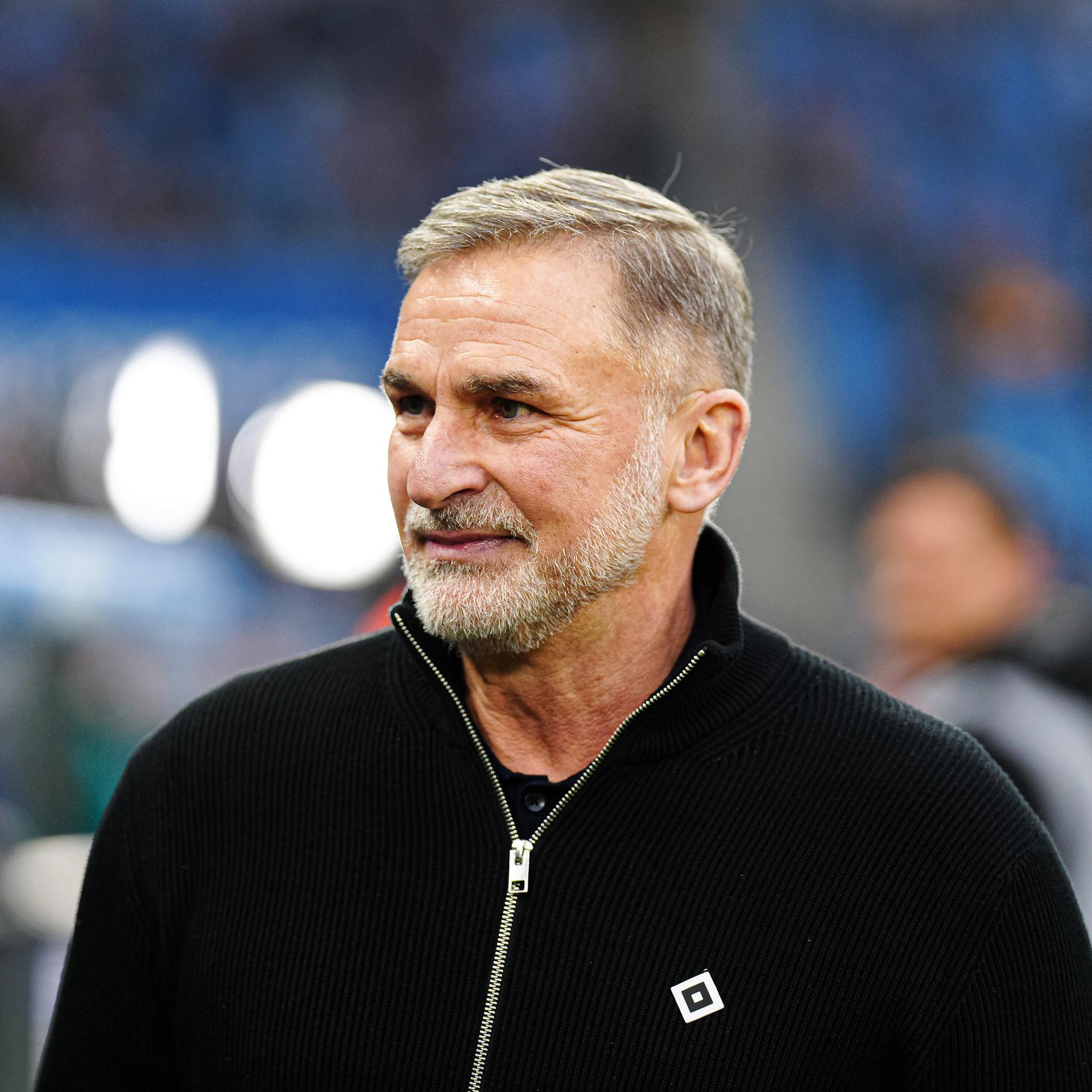 Stefan Kuntz steht am Spielfeldrand. Er trägt einen schwarzen Pullover mit dem Logo des HSV darauf.