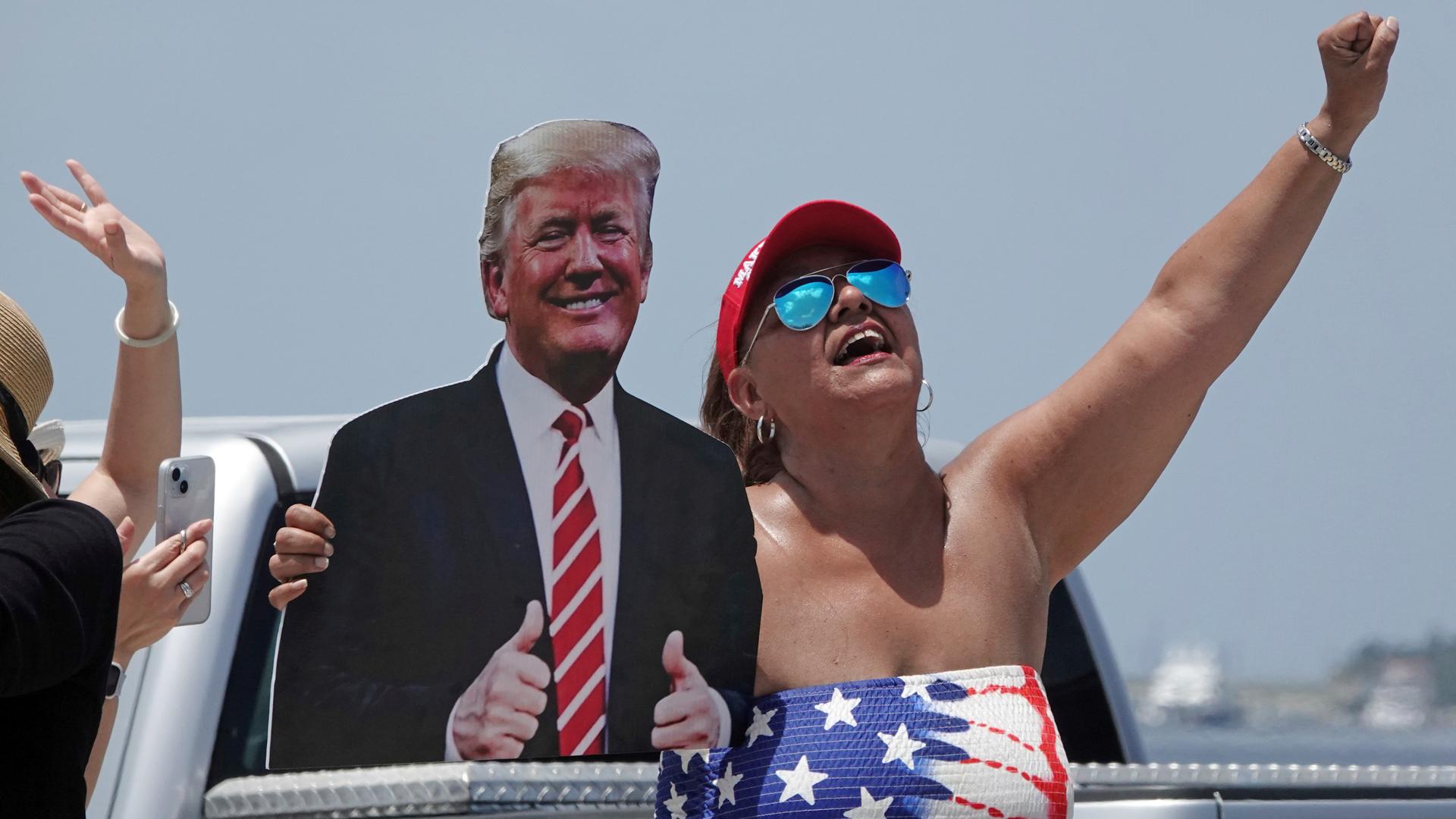 Eine Frau hält einen Pappaufsteller im Arm, auf dem Donald Trump abgebildet ist. 