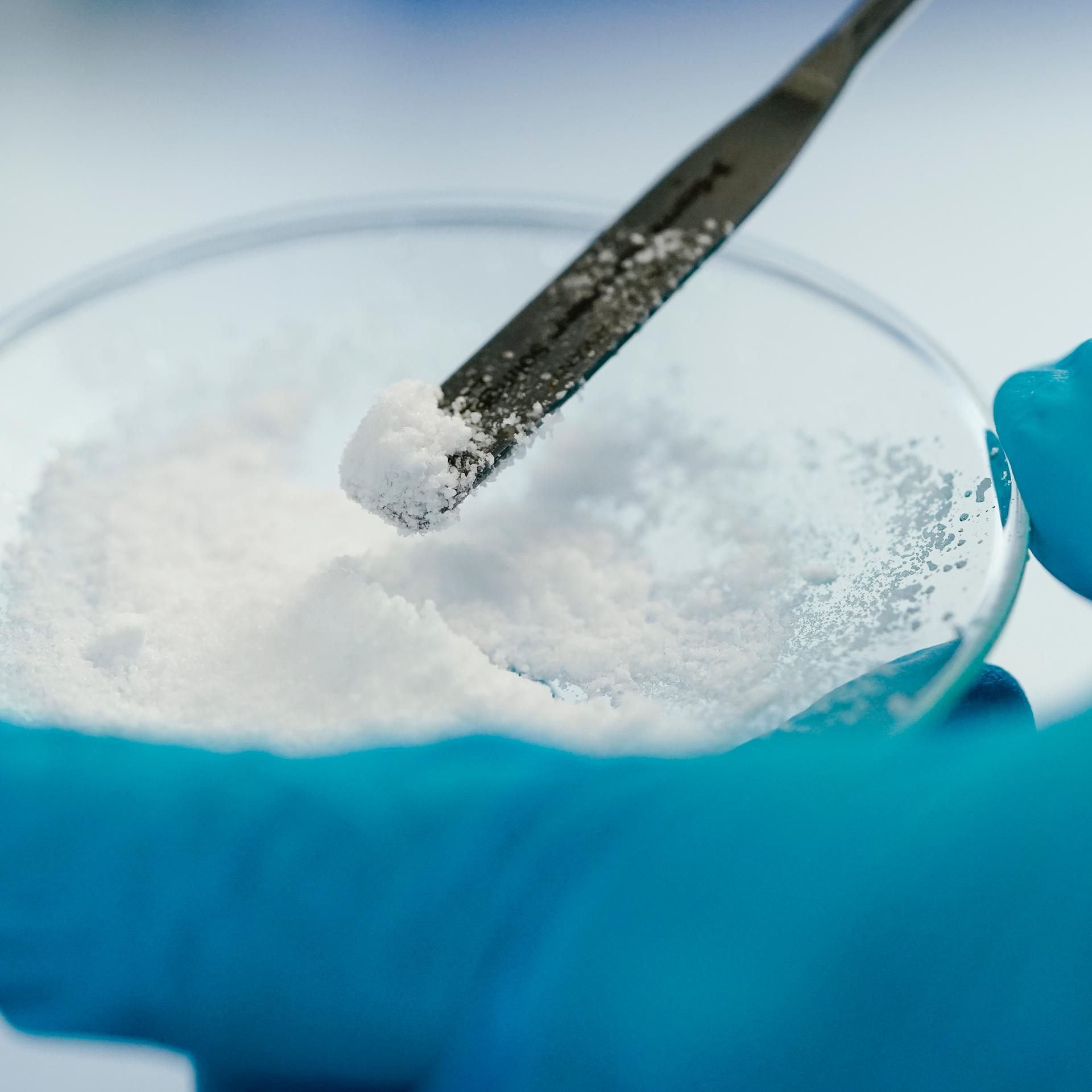 Eine Mitarbeiterin hält in einem Labor der Vulcan Energie eine Glasschale mit Lithiumchlorid in den Händen.