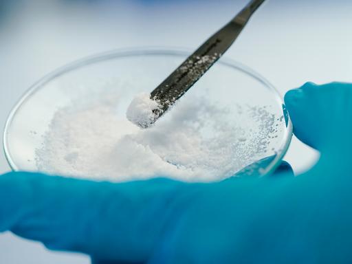 Eine Mitarbeiterin hält in einem Labor der Vulcan Energie eine Glasschale mit Lithiumchlorid in den Händen.