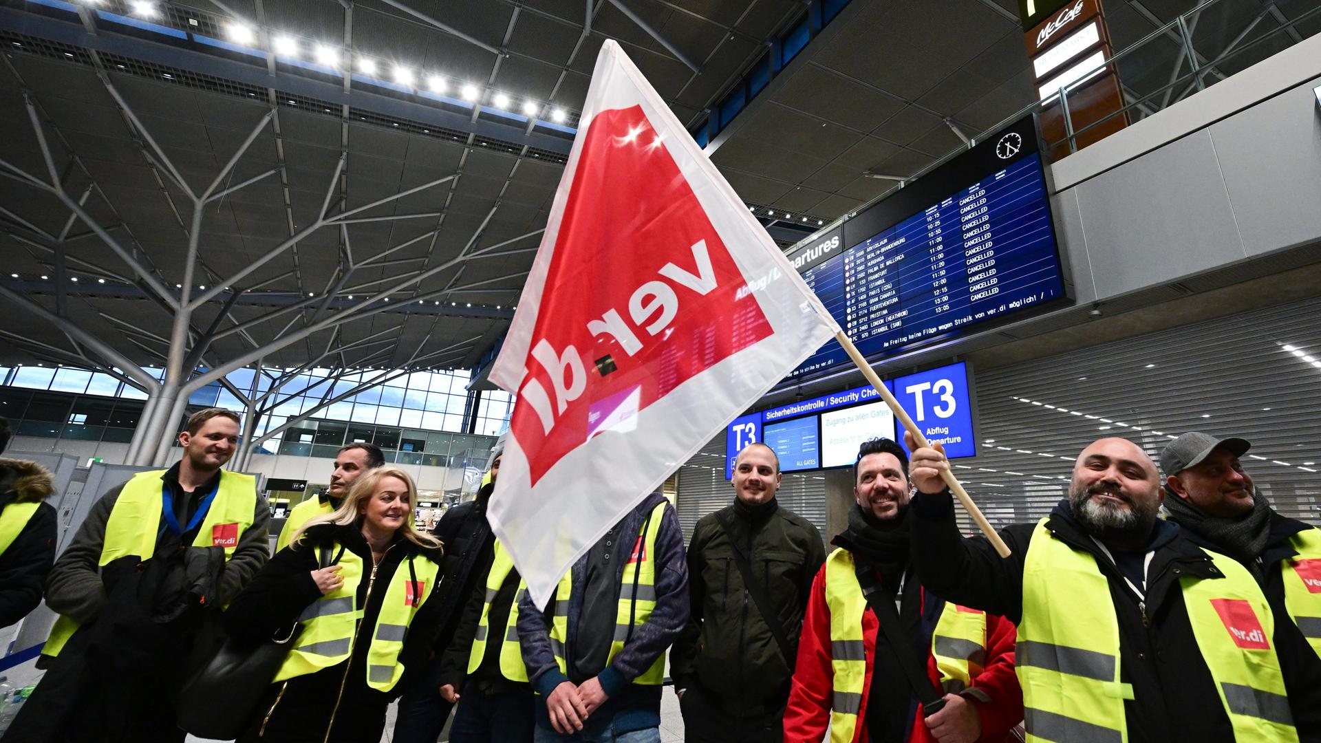 Das Foto zeigt streikende Mitarbeiter des Flughafens Stuttgart. Sie stehen mit Westen der Gewerkschaft Verdi in der leeren Abflughalle auf dem Flughafen Stuttgart.