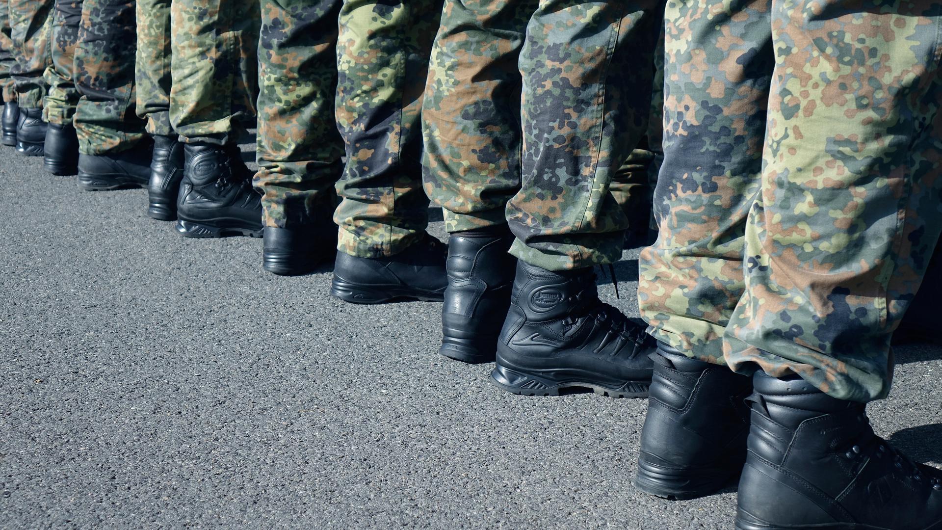 Zu sehen sind die Beine mehrerer Bundeswehrsoldaten, die in einer Reihe stehen, sie tragen Tarnkleidung. 