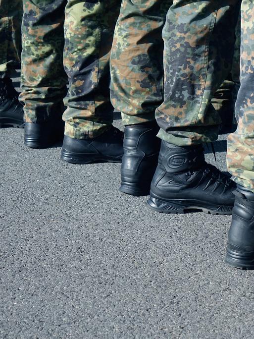 Zu sehen sind die Beine mehrerer Bundeswehrsoldaten, die in einer Reihe stehen, sie tragen Tarnkleidung. 