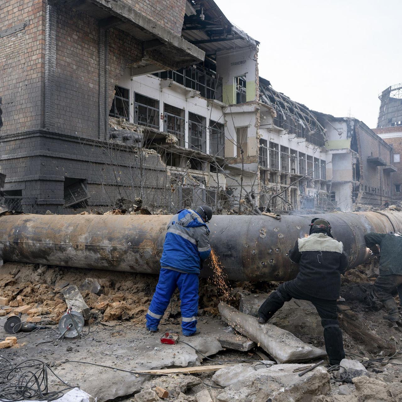 Arbeiter untersuchen ein durch einen russischen Angriff zerstörtes Rohr in einer Energieanlage in Kiew.