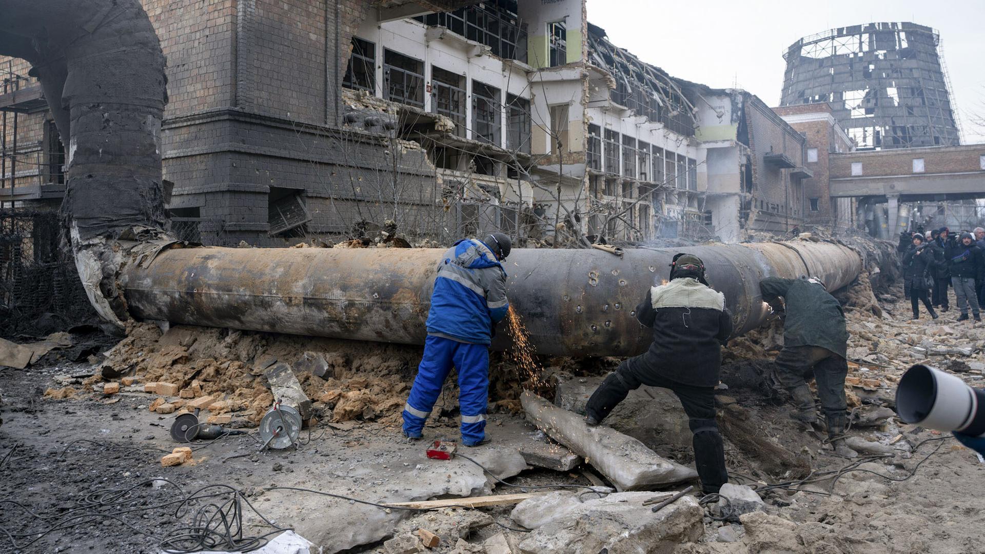 Arbeiter untersuchen ein durch einen russischen Angriff zerstörtes Rohr in einer Energieanlage in Kiew.