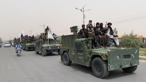 Bewaffnete Taliban fahren mit einem Konvoi aus vormalig amerikanischen Armeefahryeugen durch Kandahar.