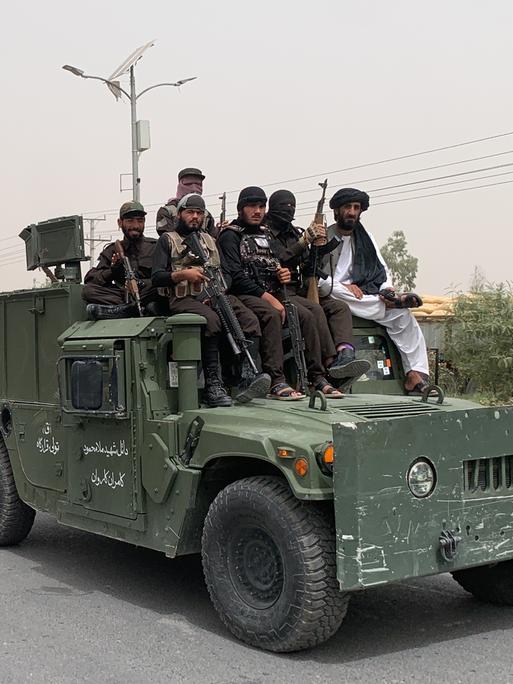 Bewaffnete Taliban fahren mit einem Konvoi aus vormalig amerikanischen Armeefahryeugen durch Kandahar.
