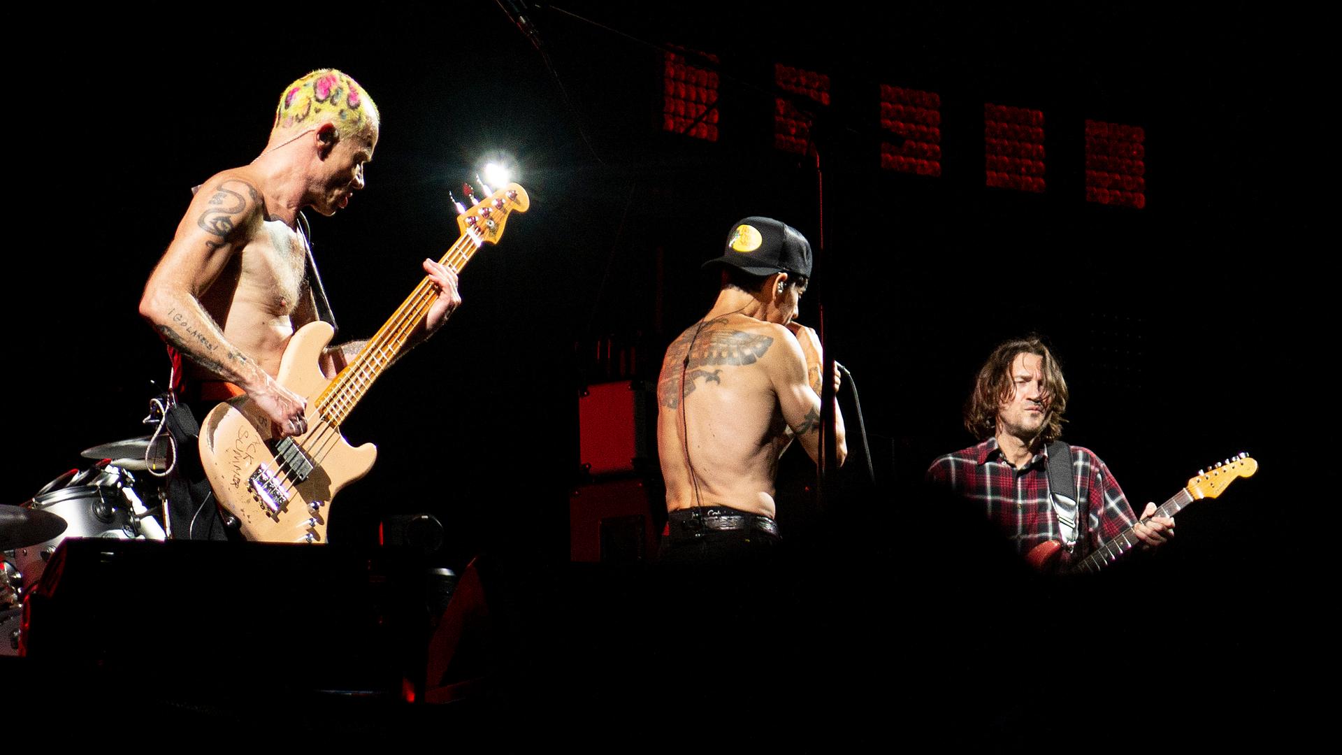 Die US-Band Red Hot Chili Peppers bei einem Konzert im Petco Park, San Diego, Kalifornien am 27. Juli 2022: Bassist Flea, Sänger Anthony Kiedis und Gitarrist John Frusciante stehen auf der Bühne, teilweise mit nacktem Oberkörper.