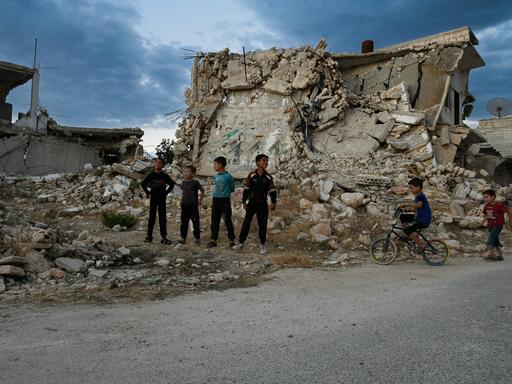 Ein paar Kinder stehen vor zerstörten Häuserruinen in der nordwestsyrischen Region Idlib