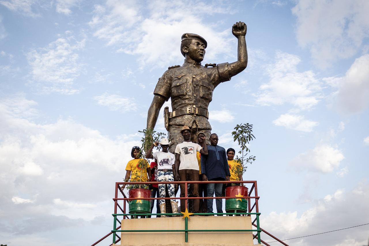 Menschen posieren für ein Foto neben der Statue von Thomas Sankara während der Zeremonie zum 34. Jahrestag.