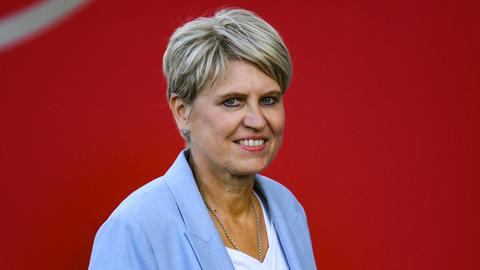 Doris Fitschen posiert im hellblauen Sakko vor einem roten Hintergrund.