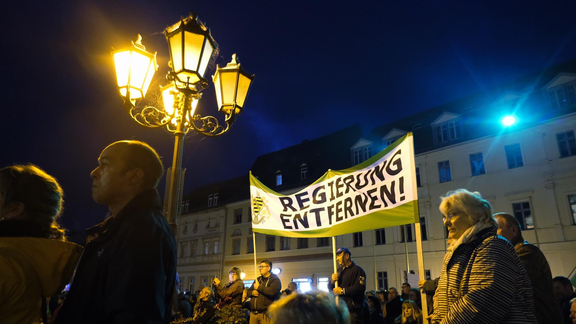 Teilnehmer einer Demonstration versammeln sich auf dem Marktplatz, im Hintergrund ein Transparent der Kleinpartei "Freie Sachsen" mit dem Schriftzug "Regierung entfernen!"