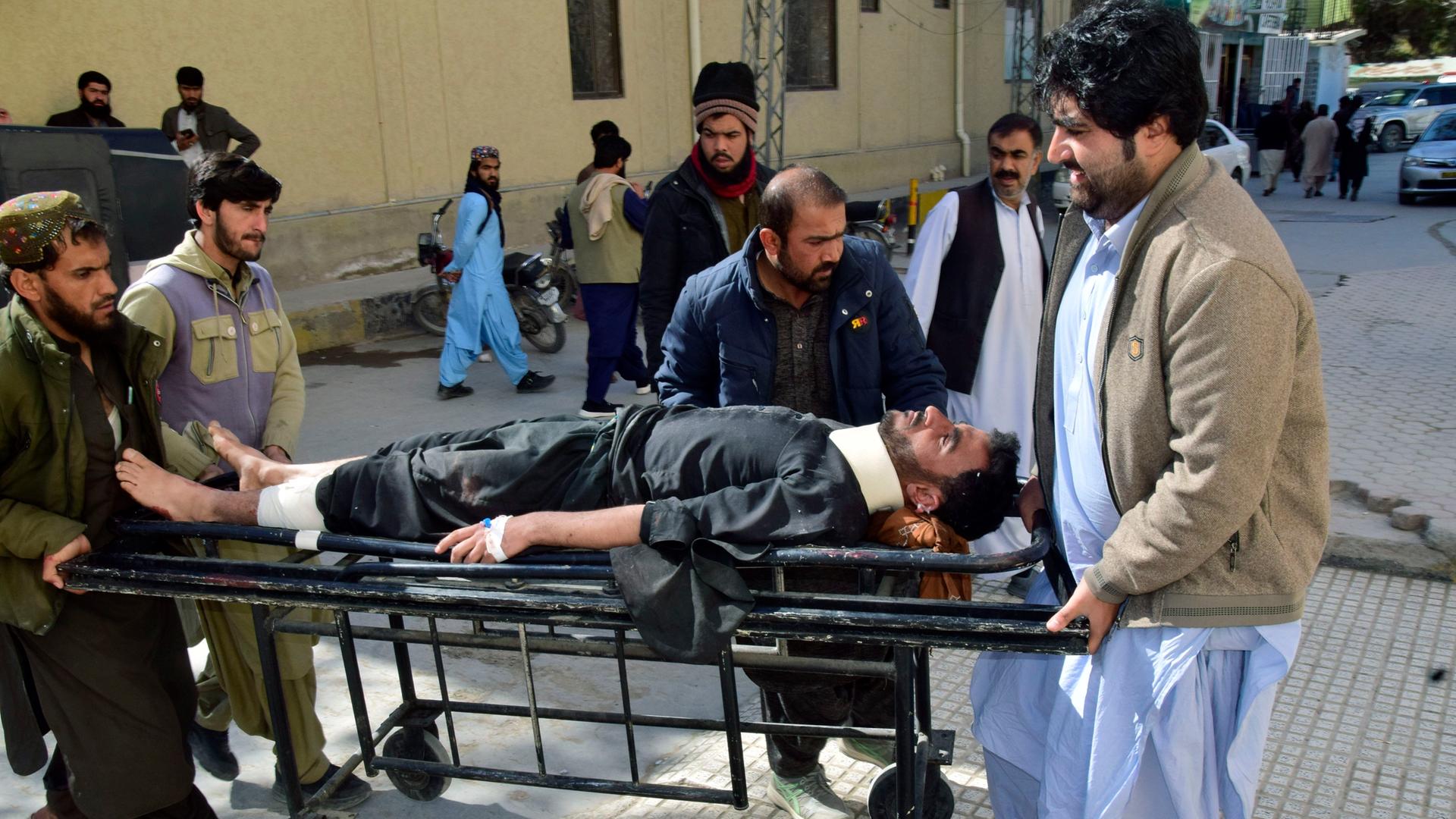 Pakistan, Quetta: Menschen transportieren eine Person auf einer Bahre nach einem Anschlag im Distrikt Pishin.
