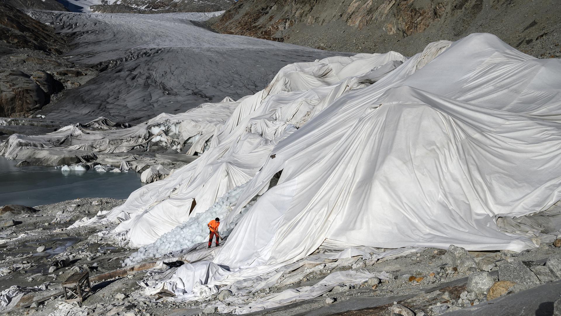 Ein Mann arbeitet am Rhonegletscher in den Alpen, der teilweise mit Isolierschaum bedeckt ist, um zu verhindern, dass er aufgrund der globalen Erwärmung schmilzt.