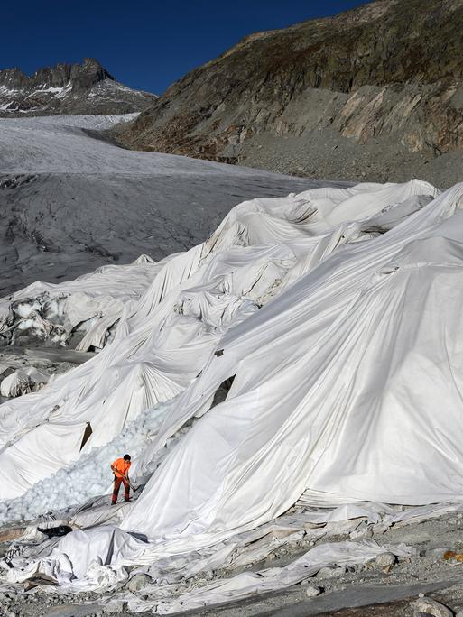 Ein Mann arbeitet am Rhonegletscher in den Alpen, der teilweise mit Isolierschaum bedeckt ist, um zu verhindern, dass er aufgrund der globalen Erwärmung schmilzt.