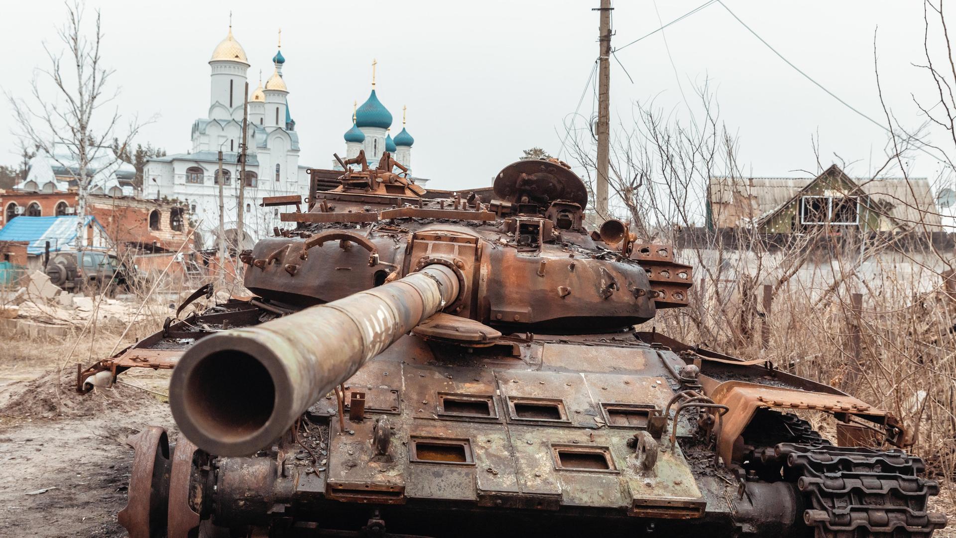 Ein ausgebrannter russischer Panzer ist auf der Straße von Swjatogirsk vor dem Hintergrund von Kirchen zu sehen. Swjatohirsk ist eine Stadt im Norden des Gebiets Donezk am Ufer des Flusses Sewerskij Donez.