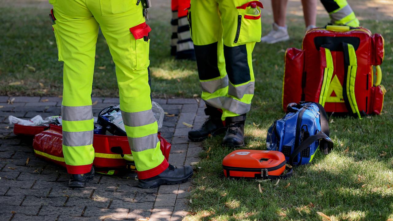 Rettungssanitäter sind in einem Park im Einsatz. Die Beine und Versorgungsmaterial sind fotografiert. 