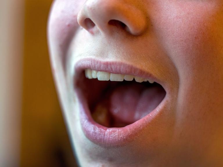 Ein geöffneter singender Mund in Nahaufnahme mit Nase, aber ohne Augenpartie. Ein geöffneter singender Mund in Nahaufnahme mit Nase, aber ohne Augenpartie.