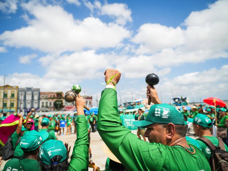 Protestierende in überwiegend grüner Kleidung vor Gebäuden auf der Straße. Manche recken ihre Fäuste in die Höhe. Protestierende in überwiegend grüner Kleidung vor Gebäuden auf der Straße. Manche recken ihre Fäuste in die Höhe.