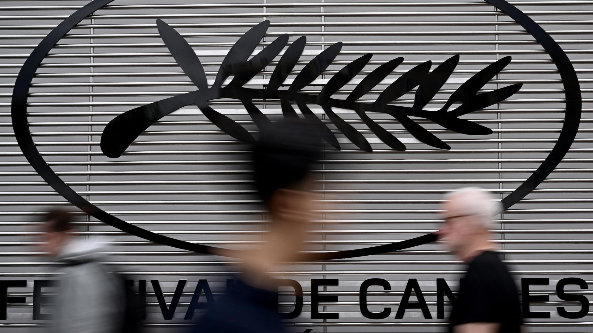 Fußgänger laufen am Logo des Filmfestivals von Cannes in Frankreich vorbei.