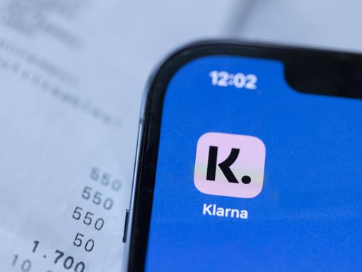 Ein Smartphone mit der Klarna-App vor ein paar Rechnungen