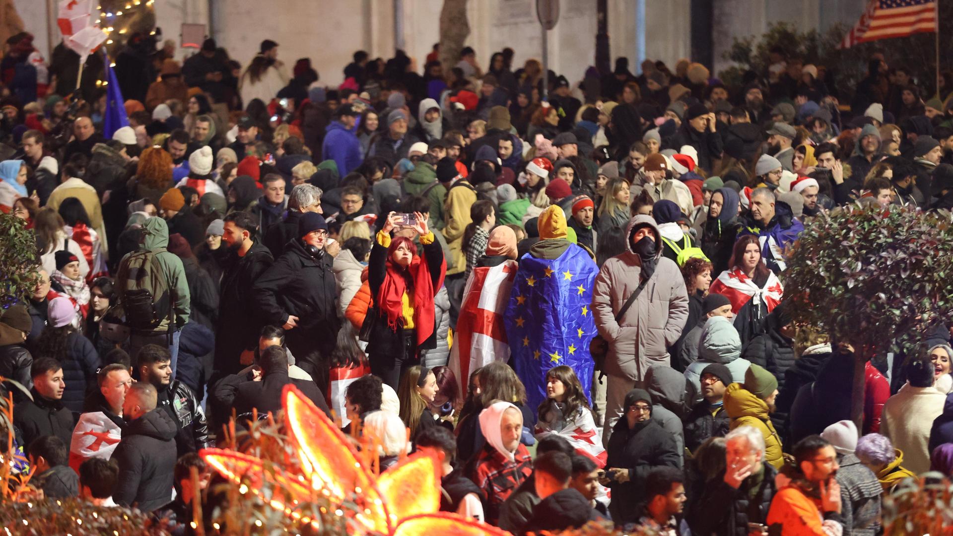 Die Menschen protestieren in der Silvesternacht mit georgischen und EU-Flaggen auf der Straße gegen die Regierung.