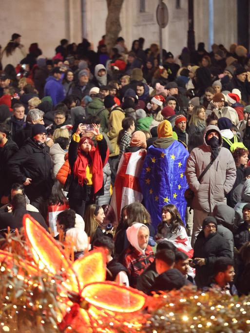 Die Menschen protestieren in der Silvesternacht mit georgischen und EU-Flaggen auf der Straße gegen die Regierung.