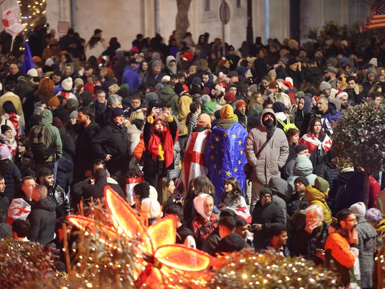 Die Menschen protestieren in der Silvesternacht mit georgischen und EU-Flaggen auf der Straße gegen die Regierung.