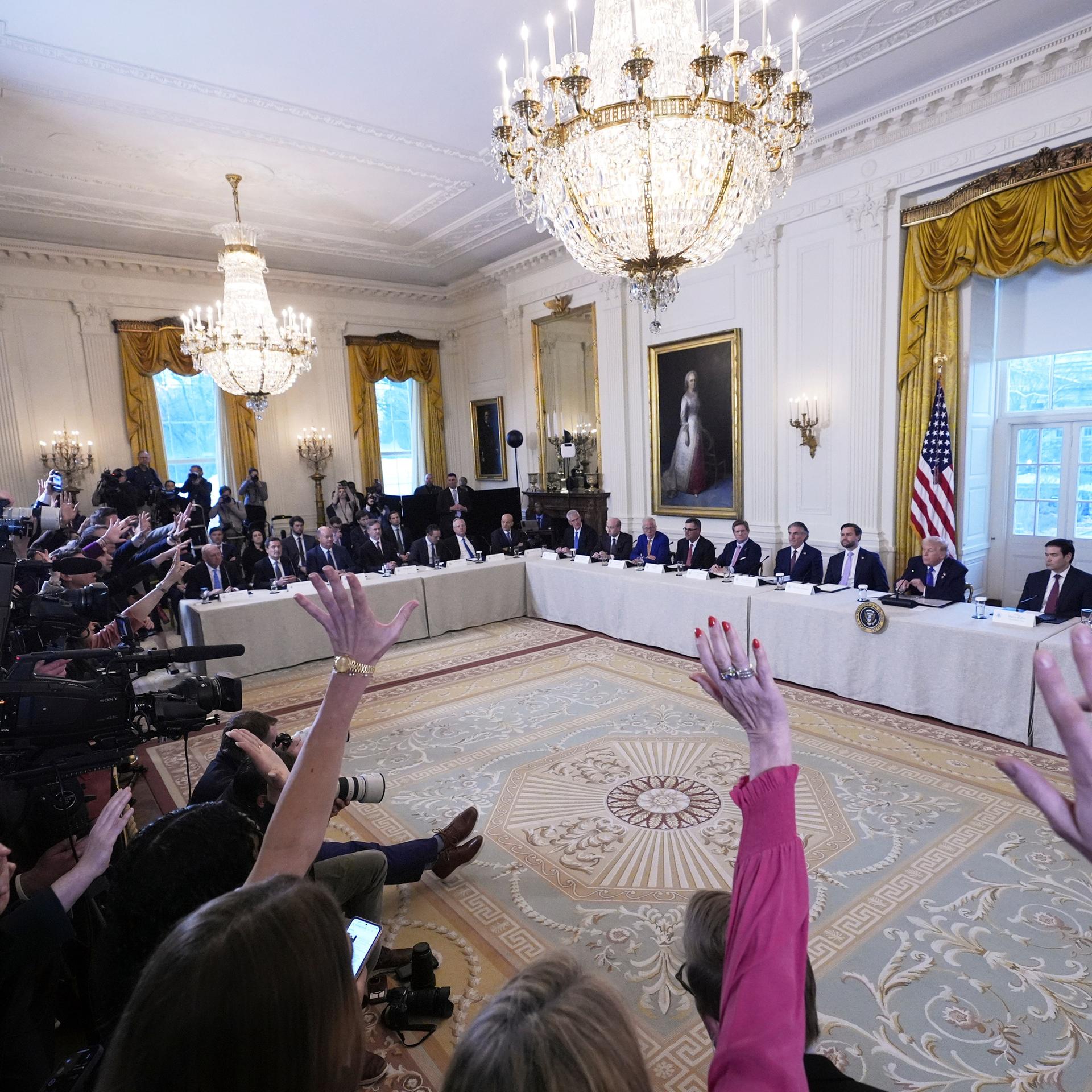 Präsident Trump bei einem Treffens mit Führungskräften der Ölindustrie im East Room des Weißen Hauses. Im Vordergrund sind Journalisten. Sie heben ihre Arme, um eine Frage zu stellen. 