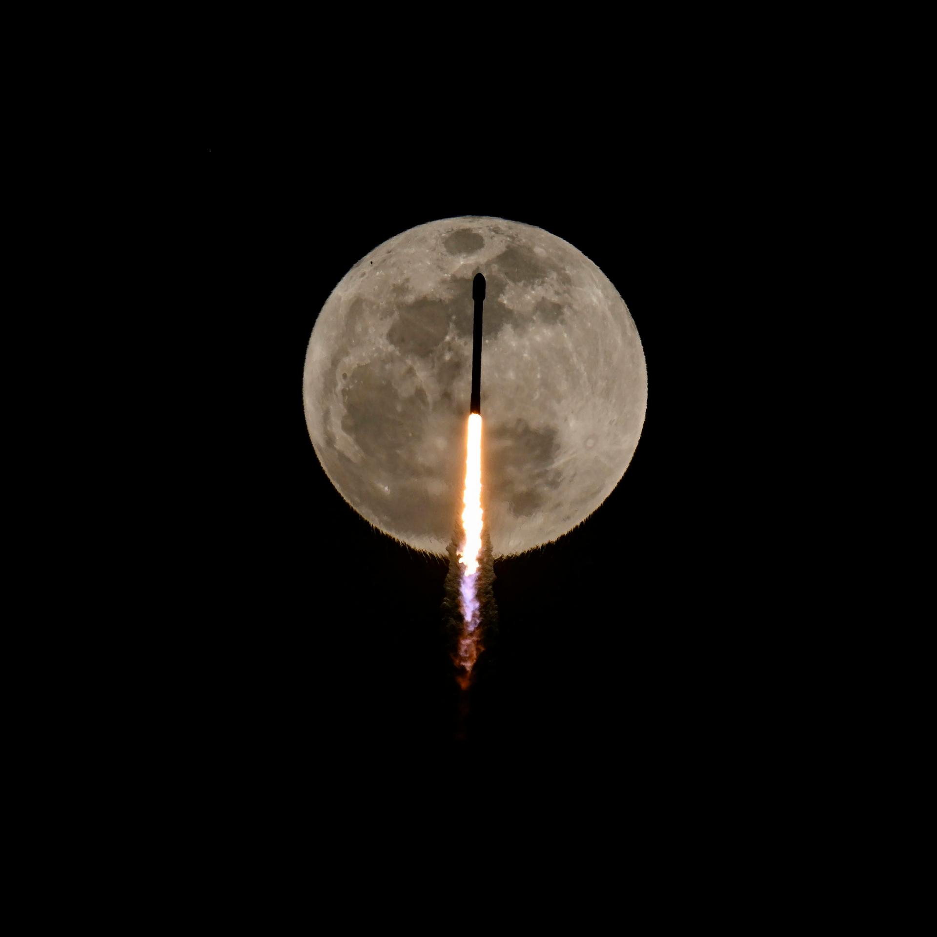 Eine SpaceX-Rakete vor dem Mond. Sie bringt Satelliten in die Erdumlaufbahn.
