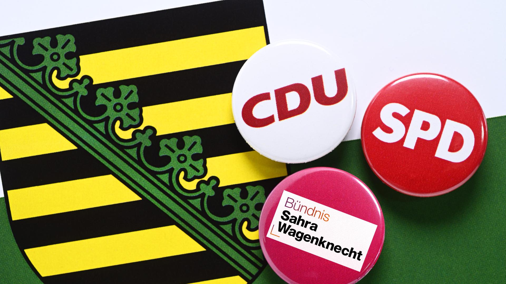 Parteianstecker von CDU, SPD und Bündnis Sahra Wagenknecht auf dem Wappen von Sachsen