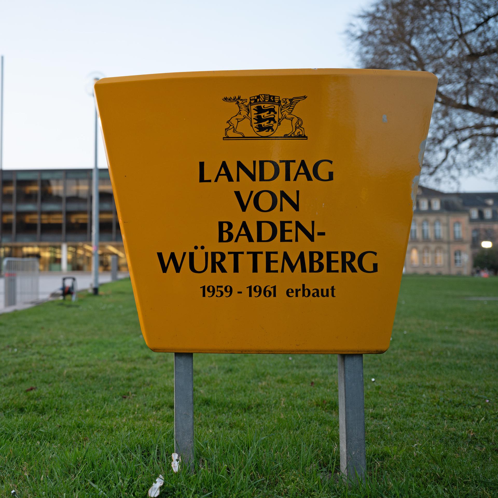 Am Landtag von Baden-Württemberg sind Absperrungen zu sehen, im Vordergrund steht ein großes Schild mit der Aufschrift: "Landtag von Baden-Württemberg 1959-1961 erbaut"