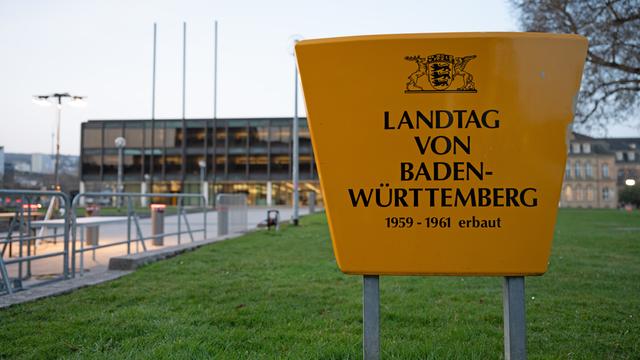 Am Landtag von Baden-Württemberg sind Absperrungen zu sehen, im Vordergrund steht ein großes Schild mit der Aufschrift: "Landtag von Baden-Württemberg 1959-1961 erbaut"