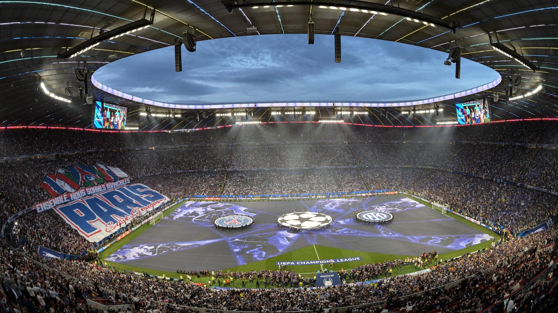 Blick in das Stadion in München, auf der Tribüne links ist ein riesiges Banner mit dem Schriftzug "Paris" über dem Publikum gespannt
