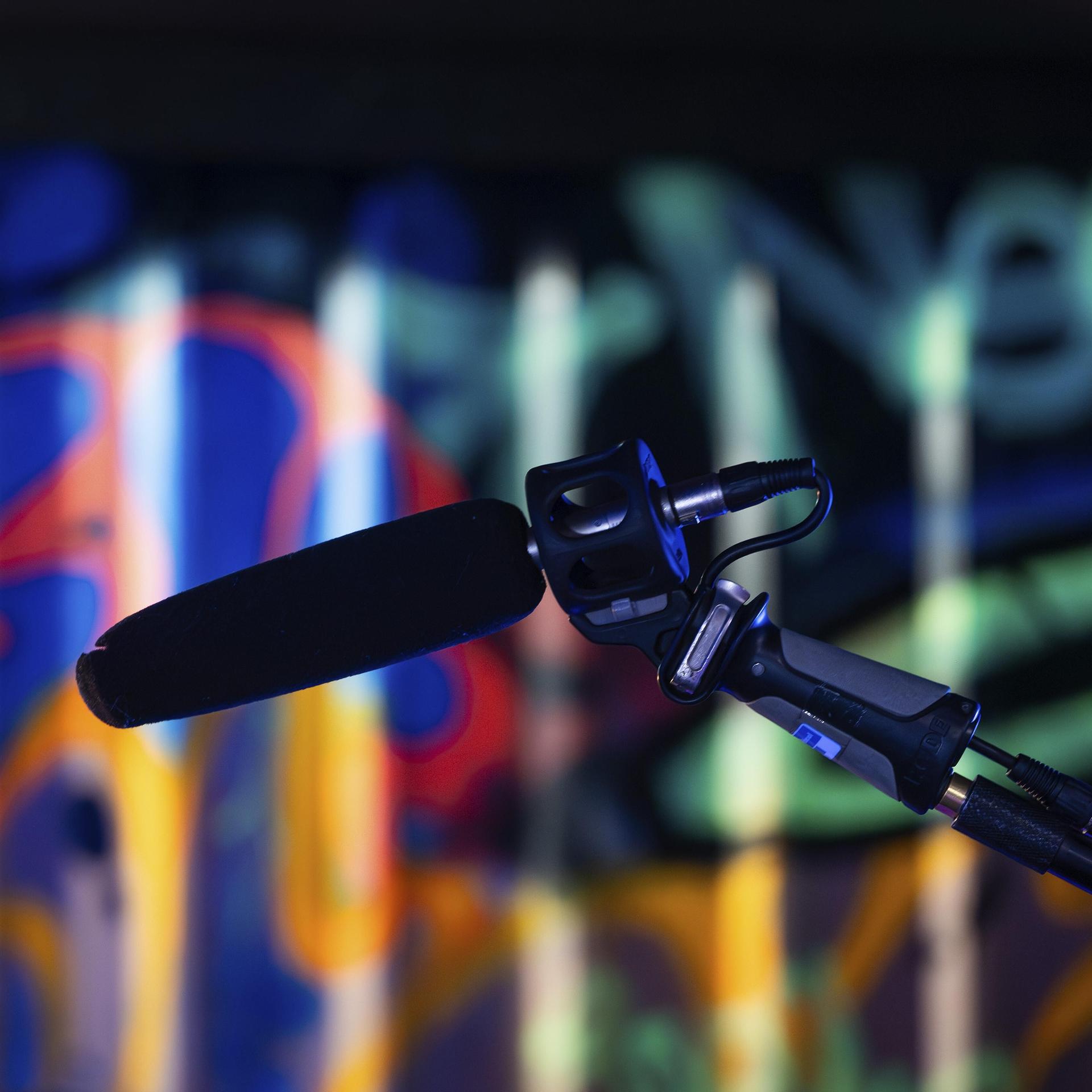 Ein Mikrofon im Vordergrund vor einem bunt beleuchteten Graffiti-Hintergrund in einem Studio, London, England, Großbritannien