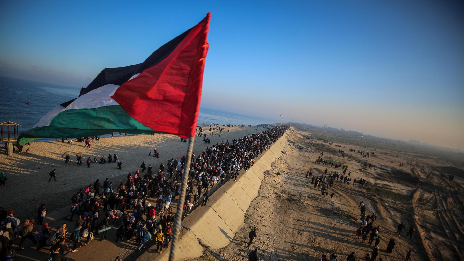 Menschenmassen unterwegs in den Norden des Gazastreifens mit der palästinensischen Flagge im Vordergrund