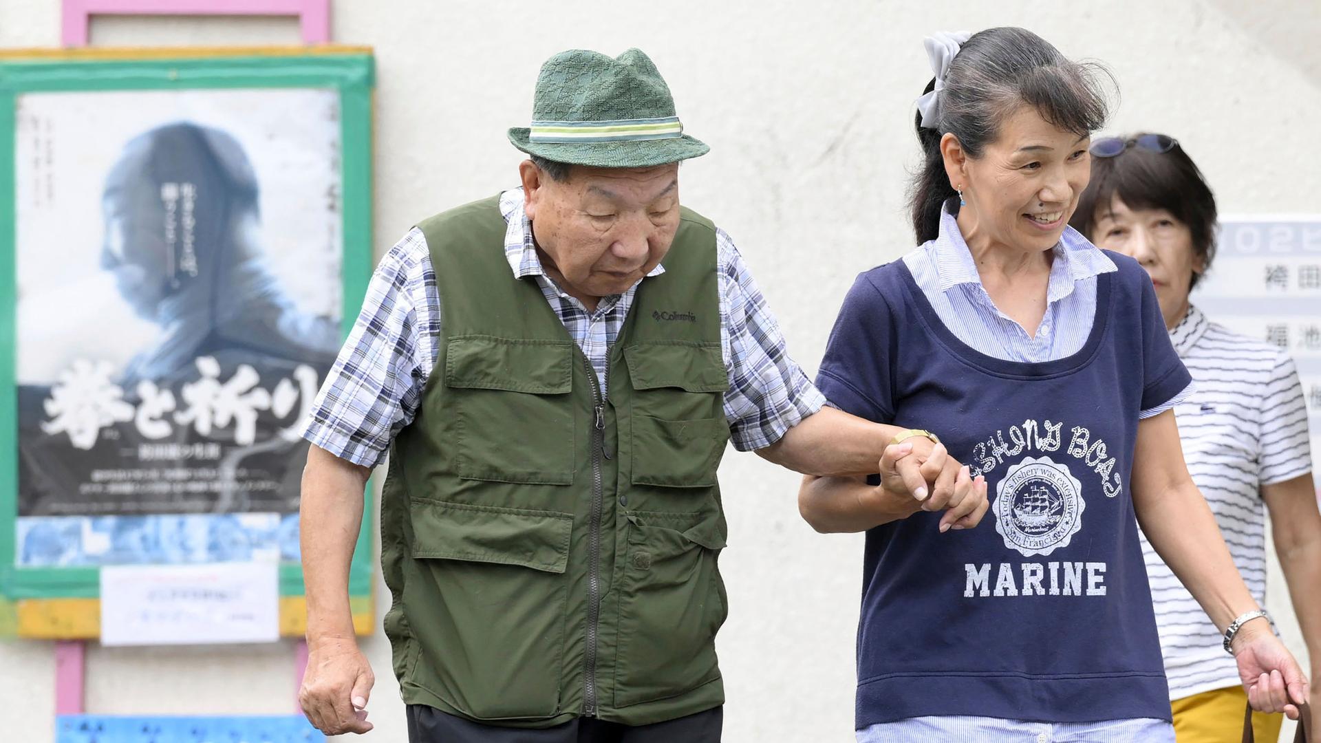 Iwao Hakamada, geht gestützt von einer Helferin, zu einem Spaziergang.