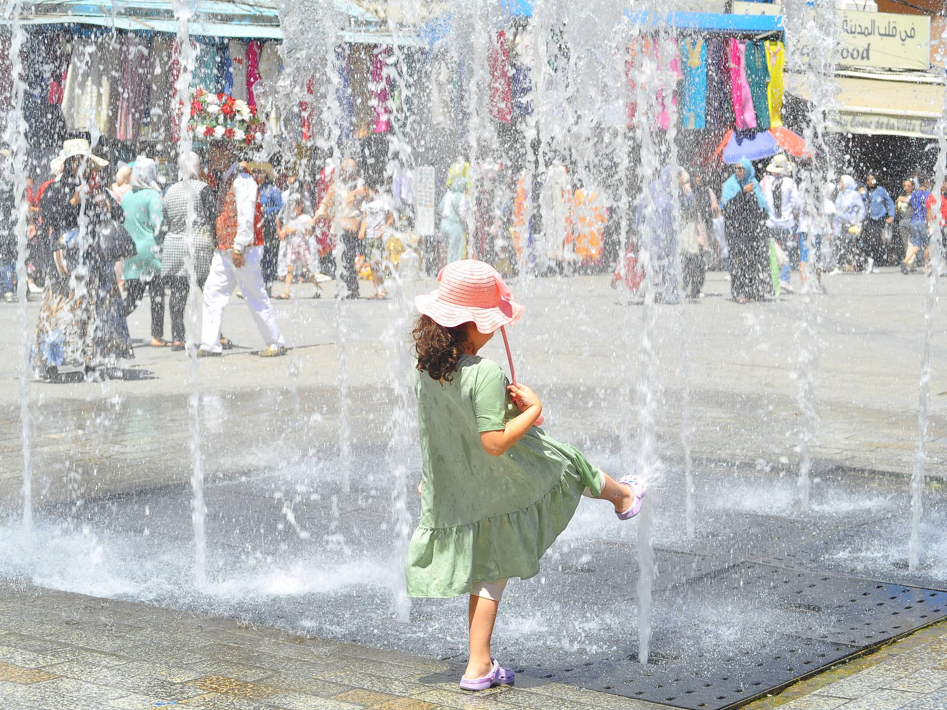 Ein Kind ist von hinten zu sehen, wie es in der tunesischen Hauptstadt Tunis an einem Springbrunnen mit Wasser spielt.