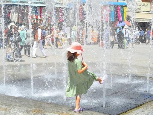 Ein Kind ist von hinten zu sehen, wie es in der tunesischen Hauptstadt Tunis an einem Springbrunnen mit Wasser spielt.