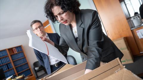 Amira Mohamed Ali steht in einem Büro und legt einen Karton mit Wahlbeschwerdeunterlagen auf den Schreibtisch