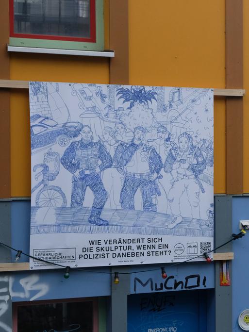 An einer Hauswand hängt ein Plakat. Darauf ist eine Zeichnung von drei Polizisten in Uniform zu sehen.