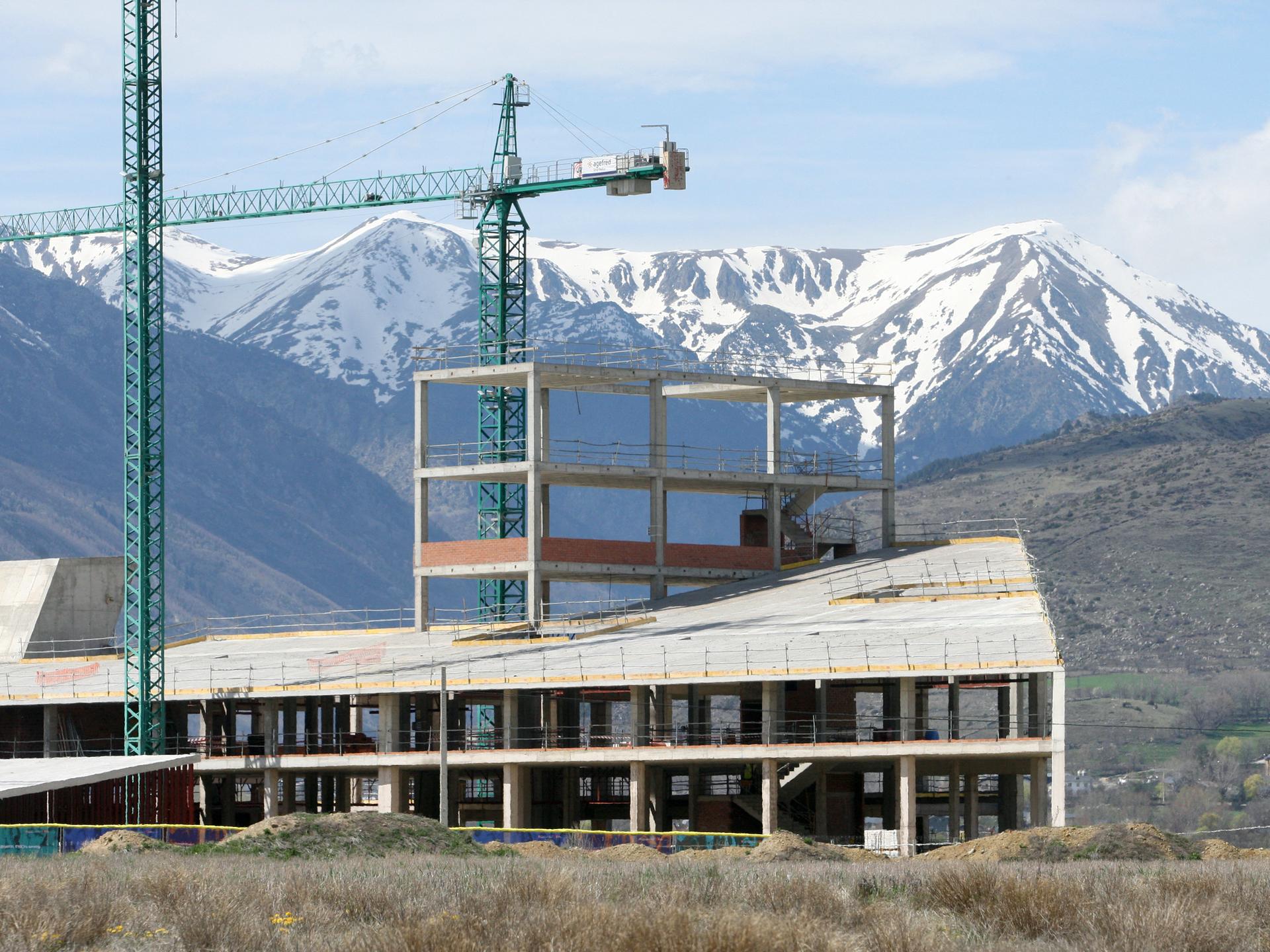 Blick auf die Baustelle des Krankenhauses, im Hintergrund sind die schneebedeckten Pyrenäen zu sehen.
