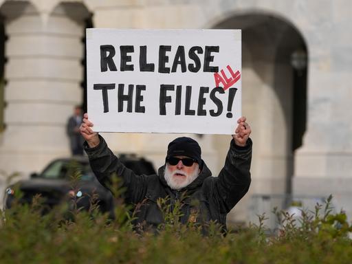 Eine Person fordert auf einem Plakat die Veröffentlichung aller Epstein-Akten.