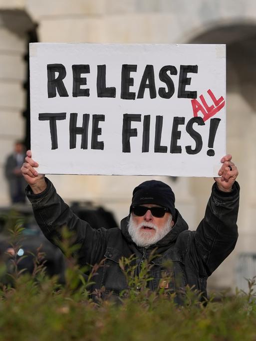 Eine Person fordert auf einem Plakat die Veröffentlichung aller Epstein-Akten.