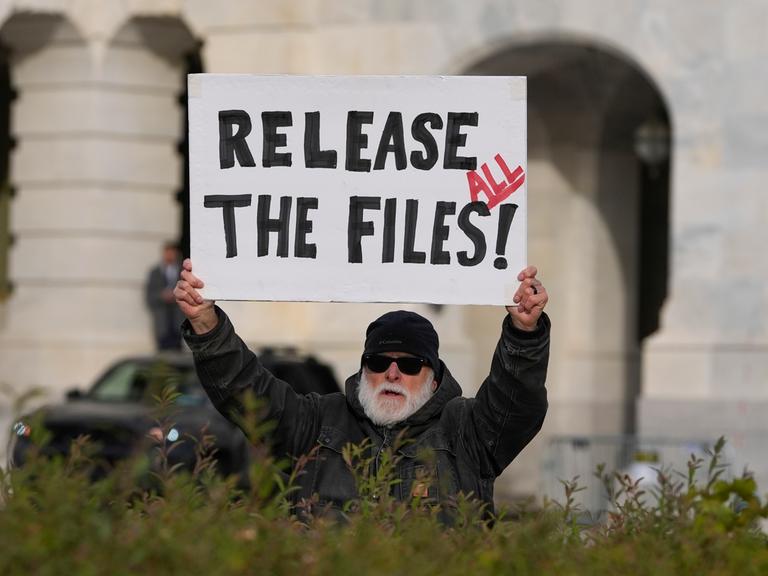 Eine Person fordert auf einem Plakat die Veröffentlichung aller Epstein-Akten.