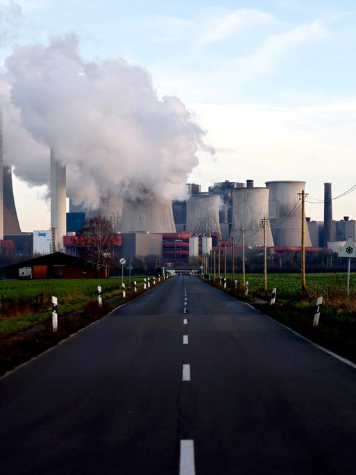 Strommasten um das Kohlekraftwerk Niederaußem des Stromkonzerns RWE. Aus dem Kraftwerk strömt eine dicke graue Wolke. (Symbolbild)