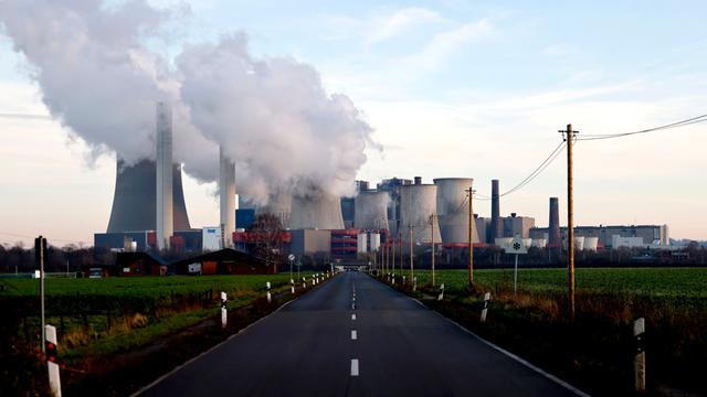 Strommasten um das Kohlekraftwerk Niederaußem des Stromkonzerns RWE. Aus dem Kraftwerk strömt eine dicke graue Wolke. (Symbolbild)